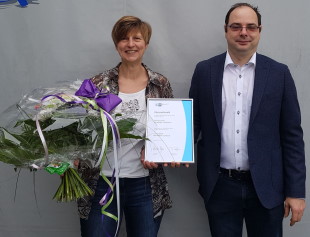 Geschäftsführer Herr Andreas Pross überreicht Mitarbeiterin Frau K. Haag einen Blumenstrauß und Ehrenurkunde des IHK zum 20-Jährigen Firmenjubiläum